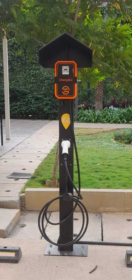 ChargeEZ EV charging station installed in residential apartment parking area with greenery in the background